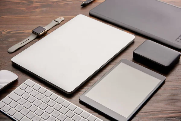 Gros plan de divers gadgets sans fil et tablette graphique sur un bureau en bois — Photo de stock