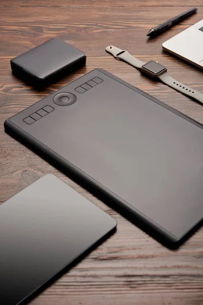 Close-up shot of professional graphics tablet with different gadgets on wooden table — Stock Photo