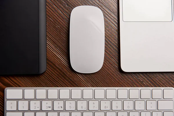 Vista parcial del portátil con ratón inalámbrico, tableta gráfica y teclado en la mesa de madera - foto de stock