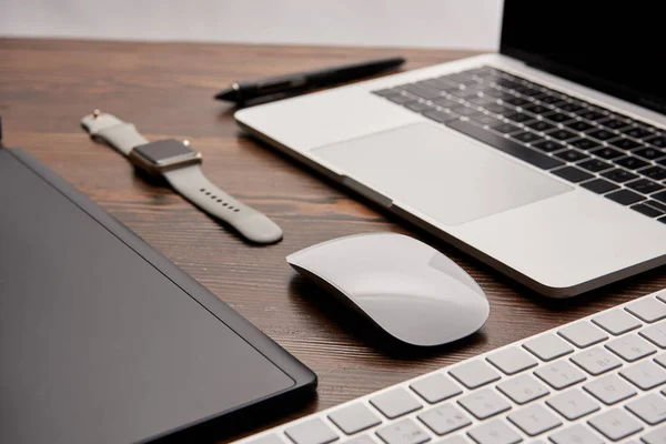 Tiro de close-up de laptop com mouse sem fio e teclado deitado na mesa de madeira com relógio inteligente e tablet gráficos — Fotografia de Stock