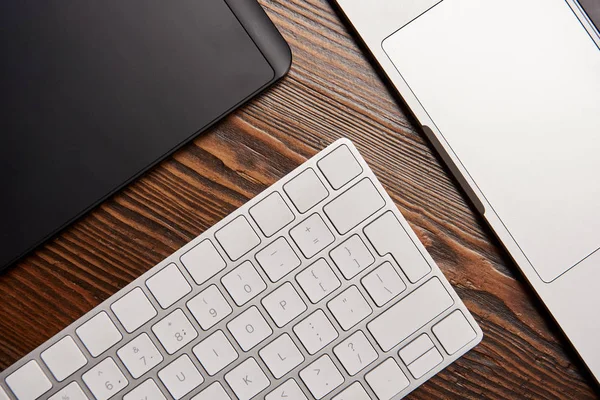 Vue du dessus de l'ordinateur portable avec clavier sans fil et tablette graphique sur table en bois — Photo de stock