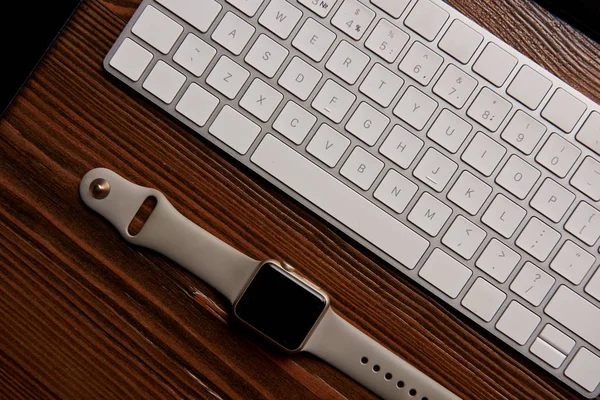 Draufsicht auf drahtlose Tastatur und Smart Watch auf Holztisch — Stockfoto