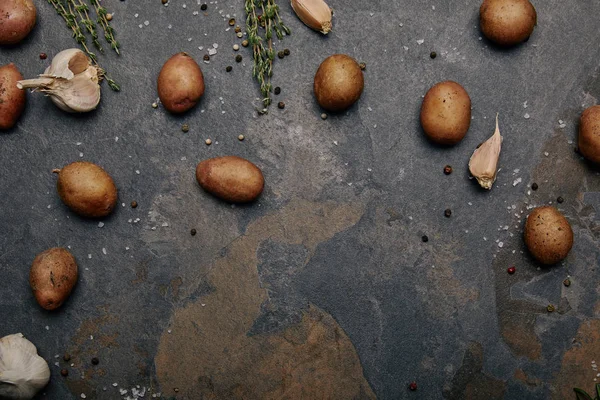 Vue de dessus des pommes de terre, épices et ail sur fond de marbre gris — Photo de stock