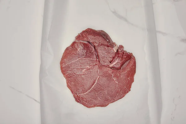 Ansicht von rohem Frischfleisch auf Kochpapier auf weißem Hintergrund — Stockfoto