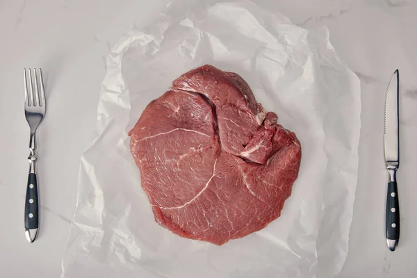 Vue du dessus de la viande fraîche crue sur papier de cuisson froissé avec fond blanc — Photo de stock