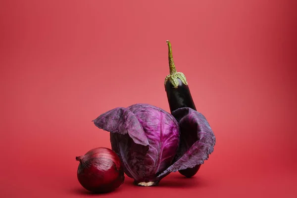 Vue rapprochée de l'oignon, du chou et de l'aubergine biologiques mûrs frais sur fond rouge — Photo de stock