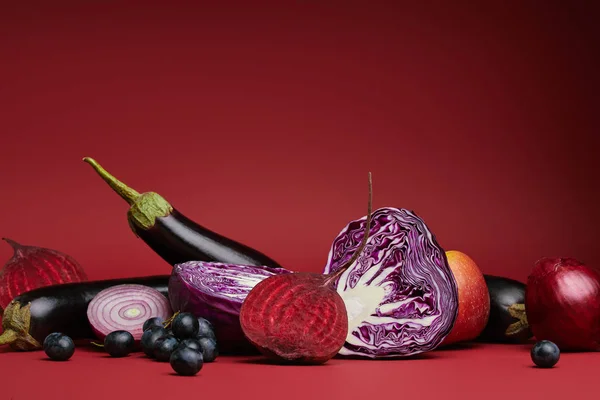 Vista de cerca de verduras y frutas orgánicas frescas maduras sobre fondo rojo - foto de stock