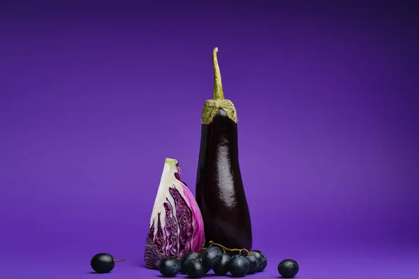 Nahaufnahme von aufgeschnittenem Kohl, Trauben und Auberginen auf violett — Stockfoto
