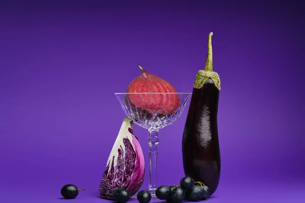 Vista de cerca de la remolacha dividida a la mitad en vidrio, repollo en rodajas, uvas y berenjena en púrpura - foto de stock