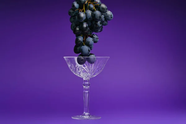 Bouquet de raisins frais mûrs et de verre sur fond violet — Photo de stock