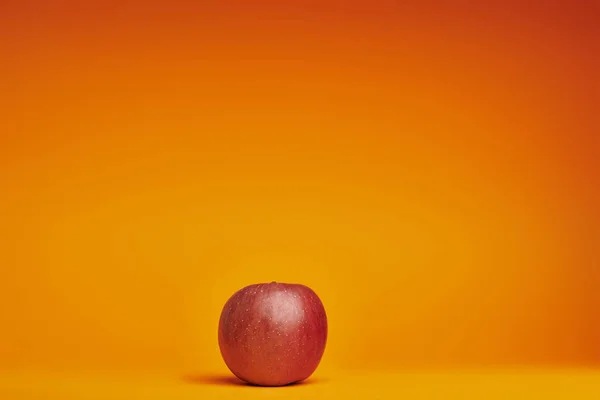 Fresh ripe organic red apple on orange background — Stock Photo