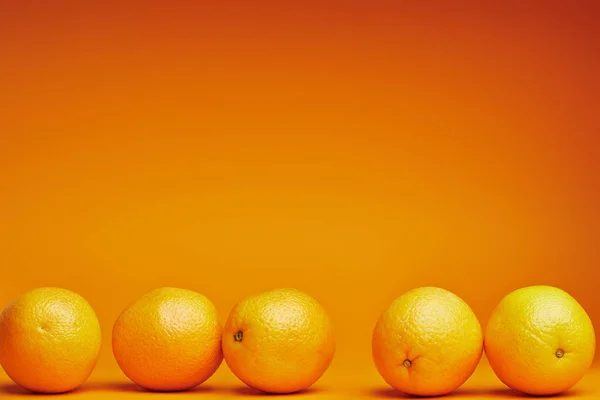 Vista de cerca de naranjas frescas maduras sobre fondo naranja - foto de stock