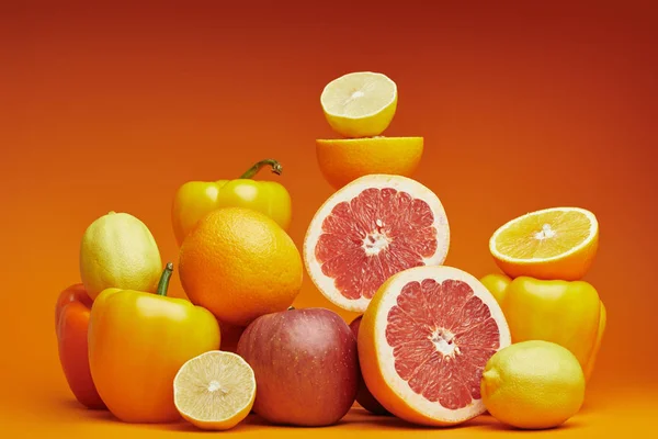 Fresh ripe citrus fruits and bell peppers on orange background — Stock Photo