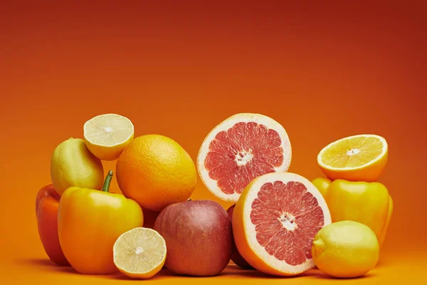 Vista de cerca de cítricos maduros frescos y pimientos sobre fondo naranja - foto de stock