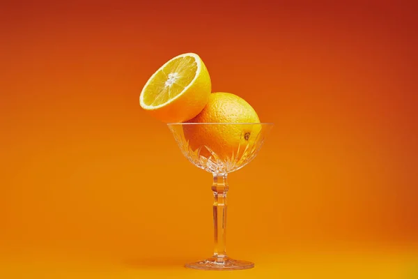 Vista de cerca de naranjas frescas maduras en vidrio sobre fondo naranja - foto de stock