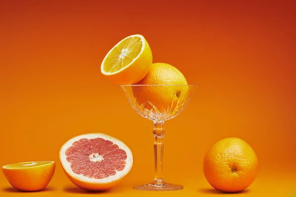Vista ravvicinata di arance mature fresche in vetro e pompelmo affettato su arancione — Foto stock
