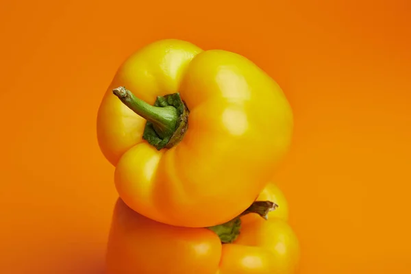 Close-up view of fresh ripe bell peppers on orange — Stock Photo