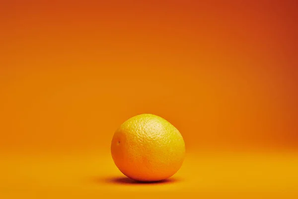 Vista de cerca de naranja entera madura fresca sobre fondo naranja - foto de stock
