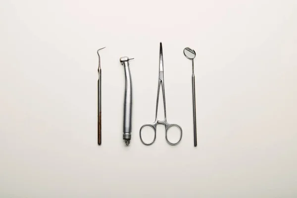 Flat lay with stainless dental instruments arranged on white tabletop, dentistry concept — Stock Photo