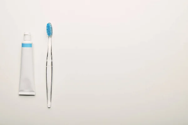 Vista superior da escova de dentes e pasta de dentes dispostos em pano de fundo branco, conceito odontológico — Fotografia de Stock