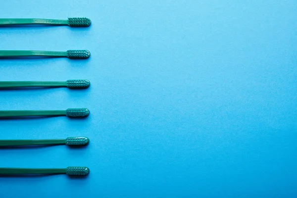 Flat lay com escovas de dentes dispostas em fundo azul — Fotografia de Stock