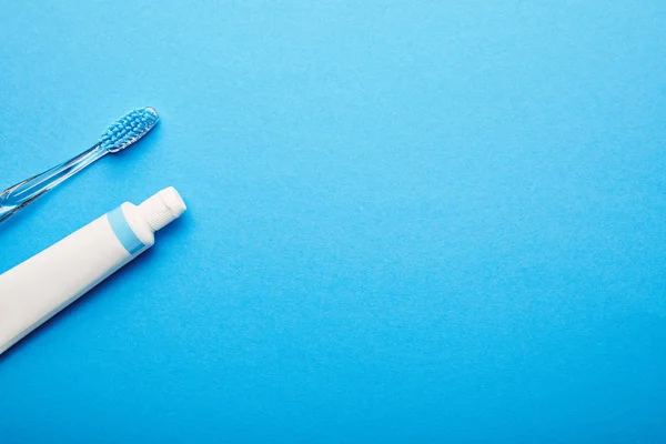 Vista superior del cepillo de dientes y la pasta de dientes dispuestos sobre fondo azul, concepto de odontología - foto de stock