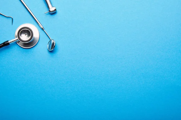 Flat lay with arranged stainless dental instruments on blue tabletop, dentistry and dental care concept — Stock Photo