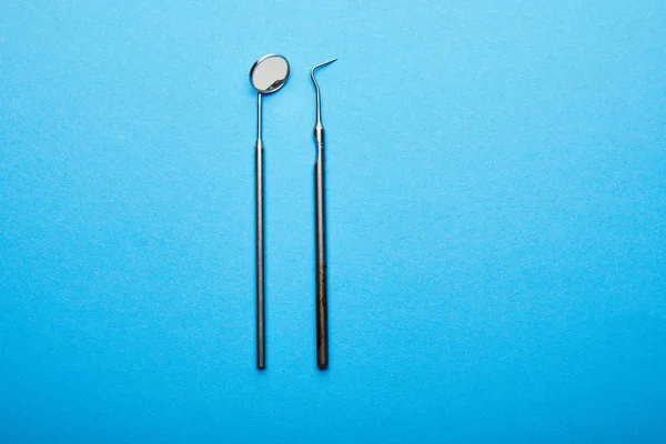 Vue de dessus du miroir et de la sonde dentaires sur la surface bleue, concept de soins dentaires — Photo de stock