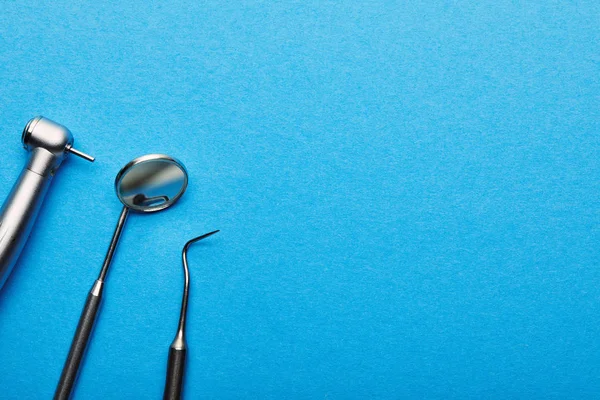 Flat lay with arranged stainless dental instruments on blue tabletop, dentistry and dental care concept — Stock Photo