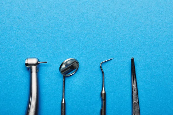 Плоский укладка с расположением нержавеющих стоматологических инструментов на синем столе, стоматология и стоматологическая концепция ухода — стоковое фото