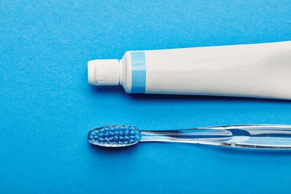 Vista superior del cepillo de dientes y la pasta de dientes dispuestos sobre fondo azul, concepto de odontología - foto de stock