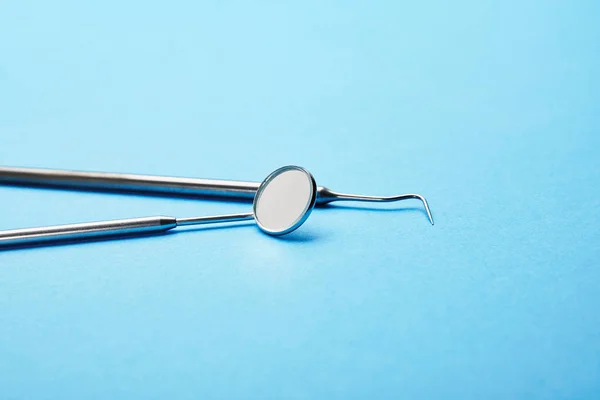 Vista de perto do espelho da boca dental e sonda na superfície azul — Fotografia de Stock