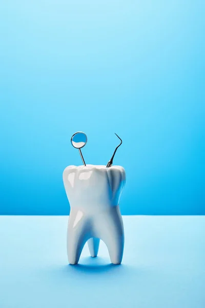 Vista de cerca del modelo de dientes, el espejo dental y la sonda en el fondo azul — Stock Photo