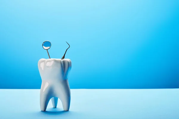 Vista de perto do modelo de dente, espelho dental e sonda no fundo azul — Fotografia de Stock