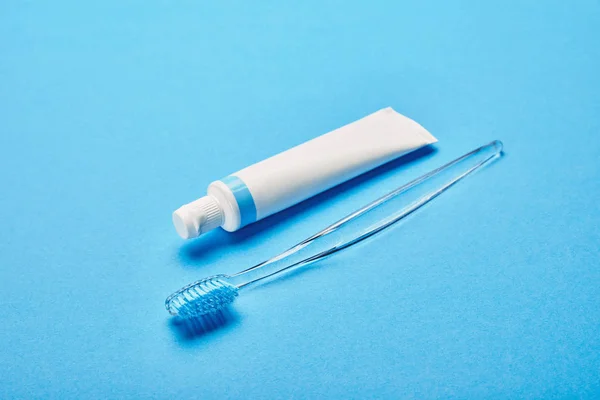 Close up view of toothbrush and toothpaste arranged on blue backdrop, dentistry concept — Stock Photo