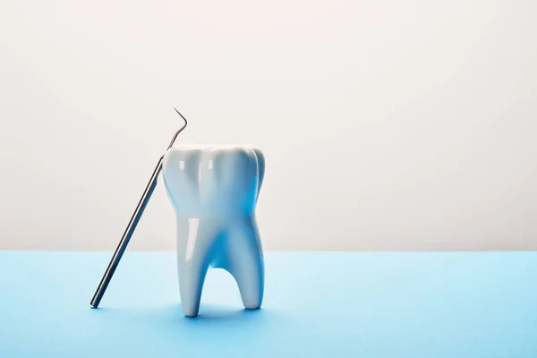 Vista de cerca del modelo de dientes y la sonda dental sobre fondo azul y blanco - foto de stock