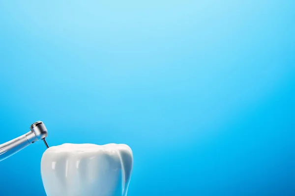 Vue rapprochée de la perceuse dentaire et du modèle de dent blanche sur fond bleu, concept de dentisterie — Photo de stock