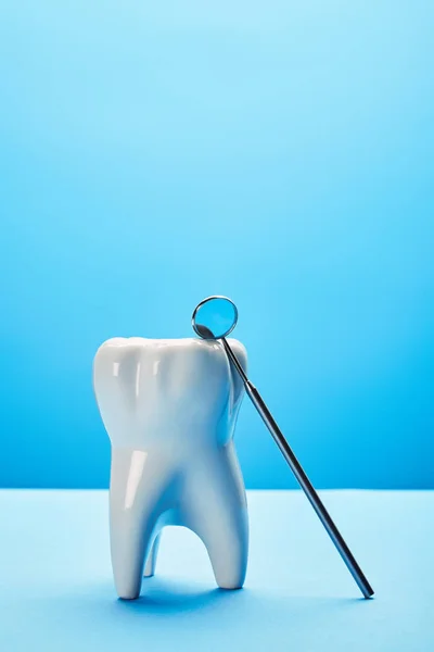 Close up view of tooth model and dental mouth mirror on blue backdrop — Stock Photo