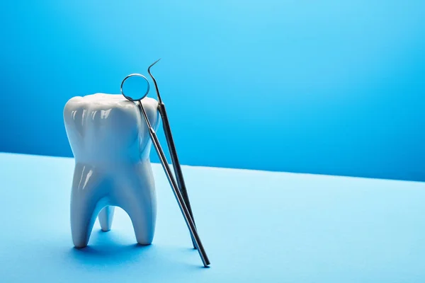 Vista ravvicinata di modello di dente, specchio dentale e sonda su sfondo blu — Stock Photo