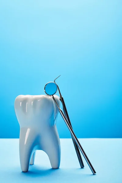 Close up view of tooth model, dental mirror and probe on blue backdrop — Stock Photo