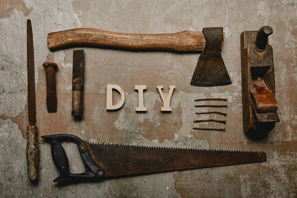 Flat lay with set of carpentry tools and diy sign on old surface — Stock Photo