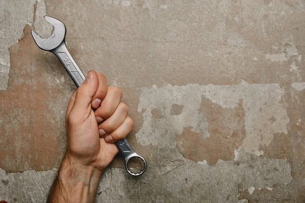 Partial view of man holding wrench on old background — Stock Photo