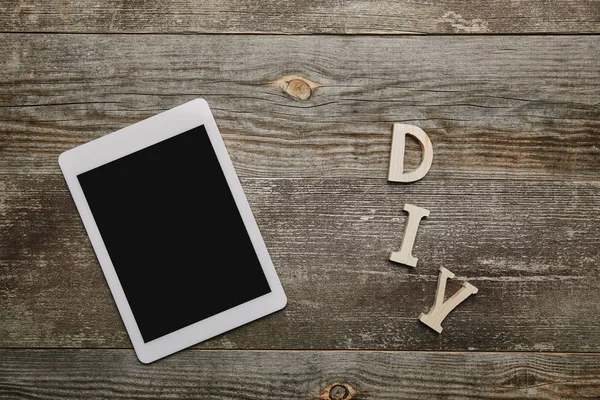 Top view of digital tablet and diy sign on wooden background — Stock Photo