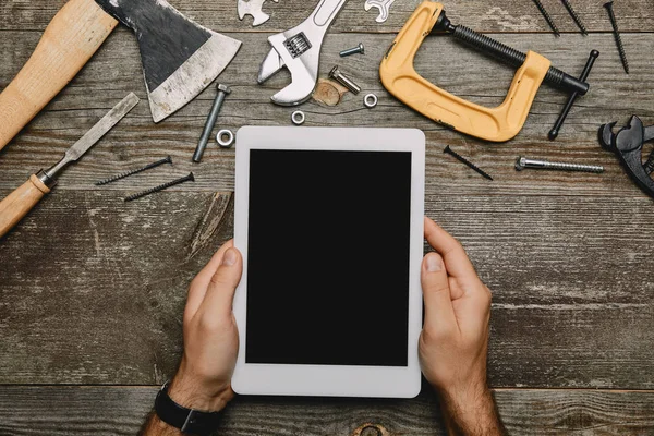 Vista parcial do trabalhador usando tablet digital em oficina com diferentes ferramentas de carpintaria — Fotografia de Stock