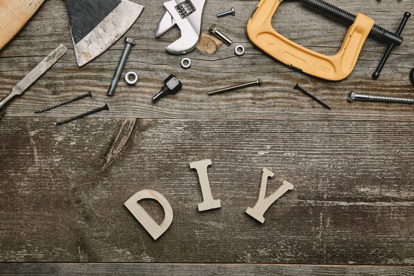 Draufsicht auf verschiedene Tischlerwerkzeuge und Diy-Zeichen auf Holzgrund — Stockfoto