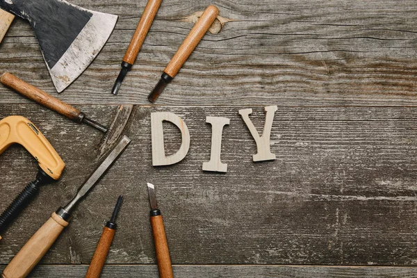 Vista superior de diferentes ferramentas de carpintaria e sinal de diy no fundo de madeira — Fotografia de Stock