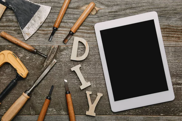 Flat lay with digital tablet, diy sign and different carpentry tools on wooden background — Stock Photo