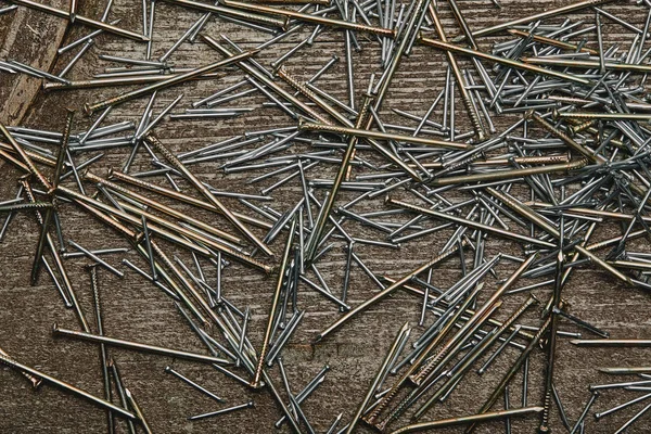 Top view of cooper and silver-colored nails on dark wooden table — Stock Photo