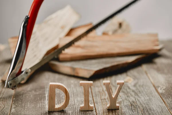 Primer plano del letrero de bricolaje en la mesa de madera en el fondo de los troncos y la sierra - foto de stock