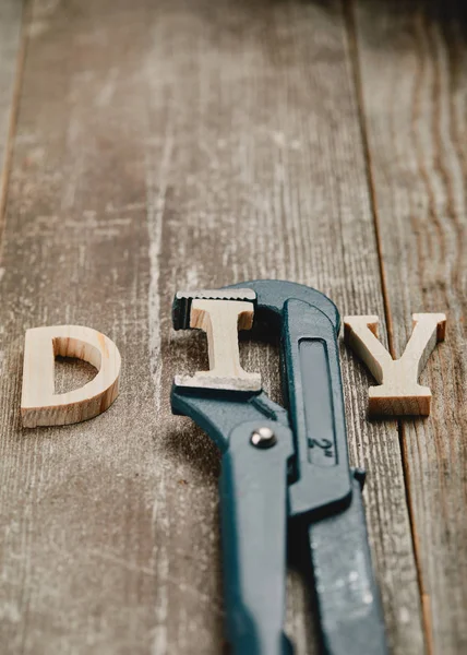 Close up of wooden diy sign and part of pipe wrench on wooden background — Stock Photo